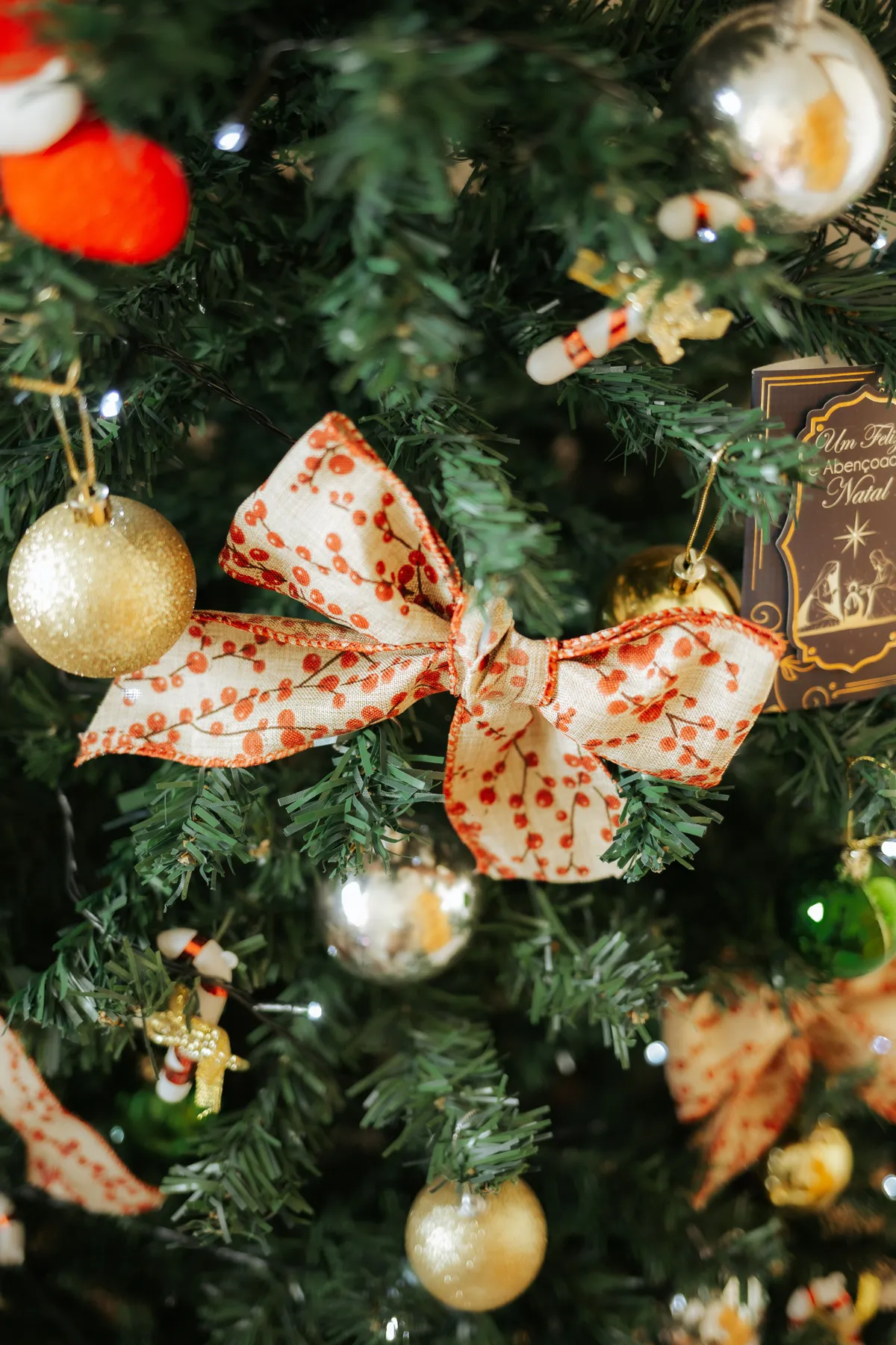 A beautifully decorated Christmas tree featuring a red bow, gold ornaments, and a festive ambiance.