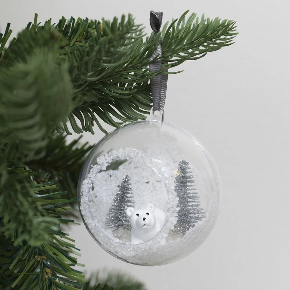 A Christmas bauble with a hole at the front decorated with artificial snow  and mini figures