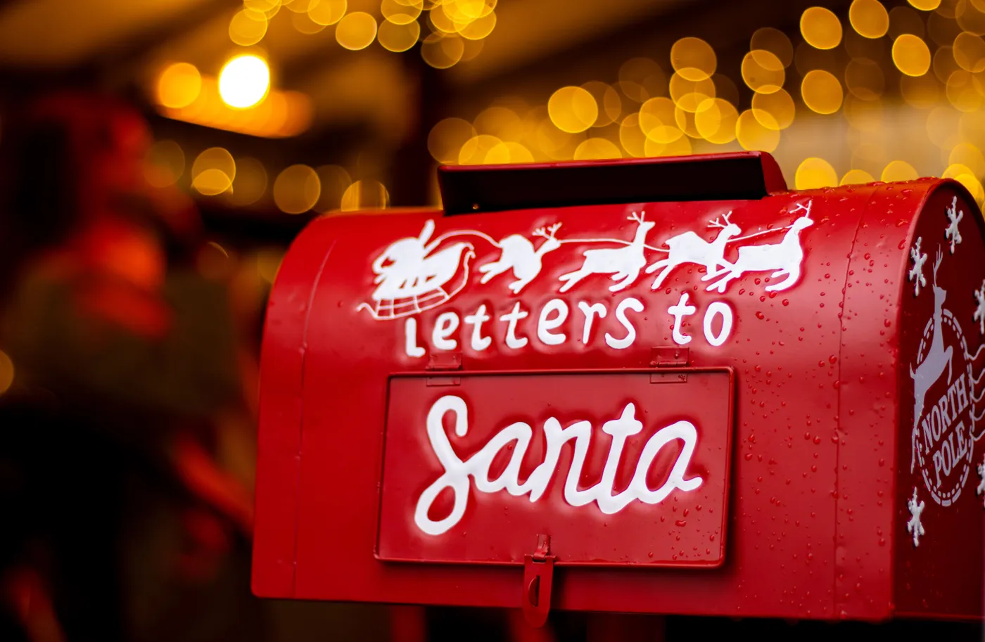 A Christmas-themed red mailbox labeled 'Letters to Santa' with bokeh lights in the background.