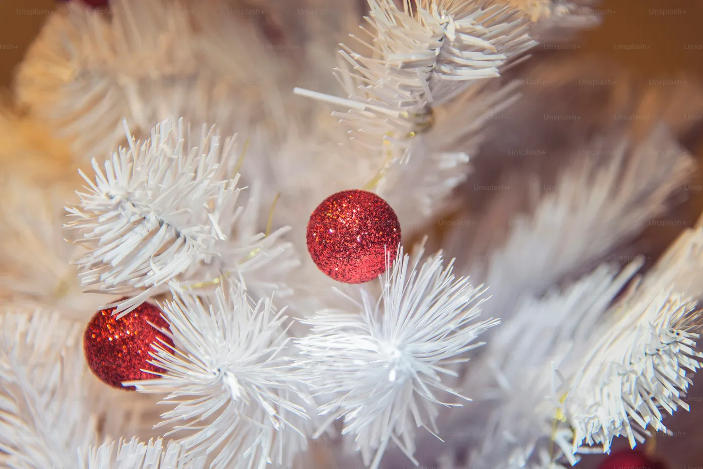 A close up of a white christmas tree with red ornaments - Photo on Unsplash+