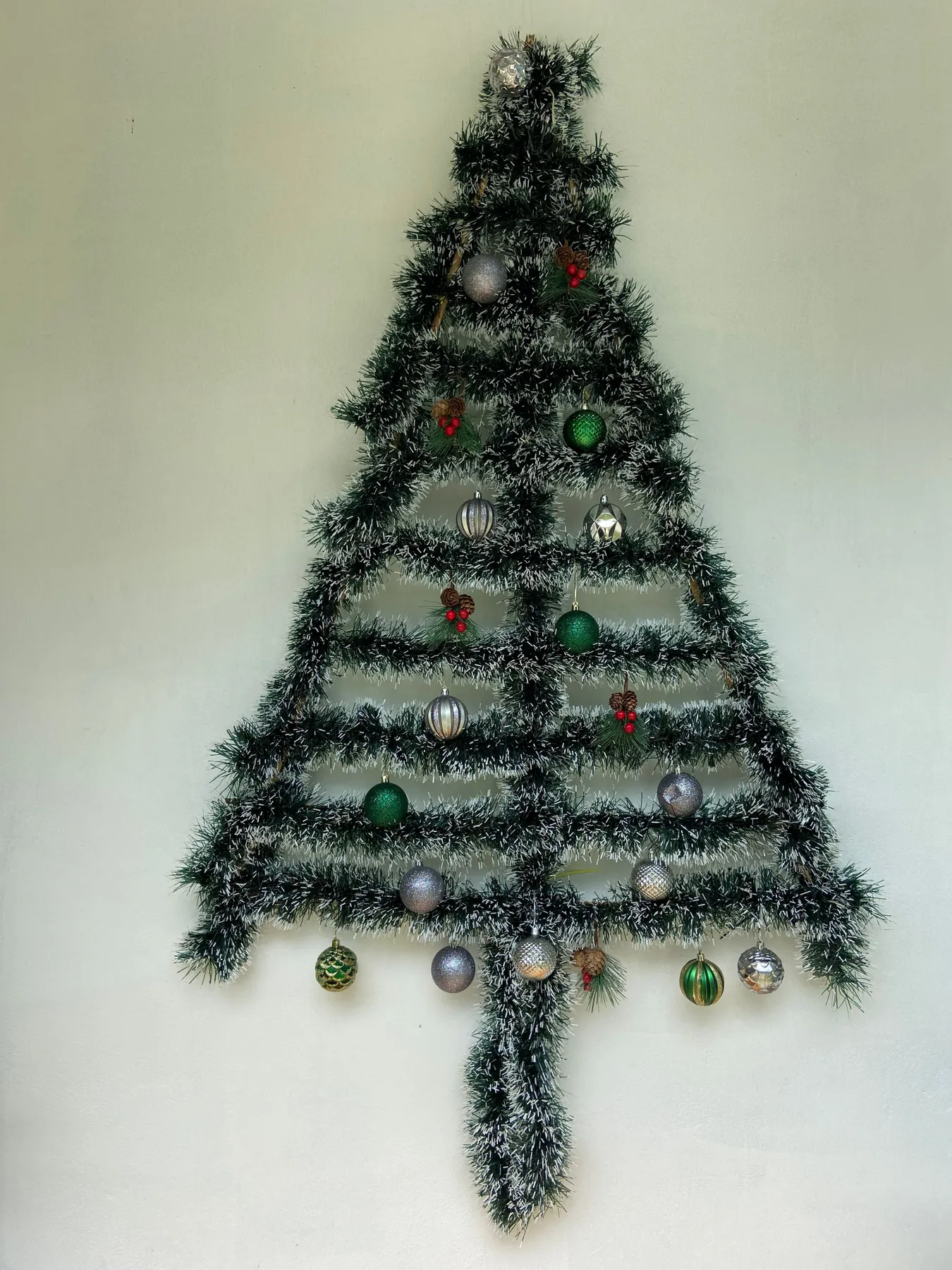A creative, wall-mounted Christmas tree decorated with ornaments and baubles.