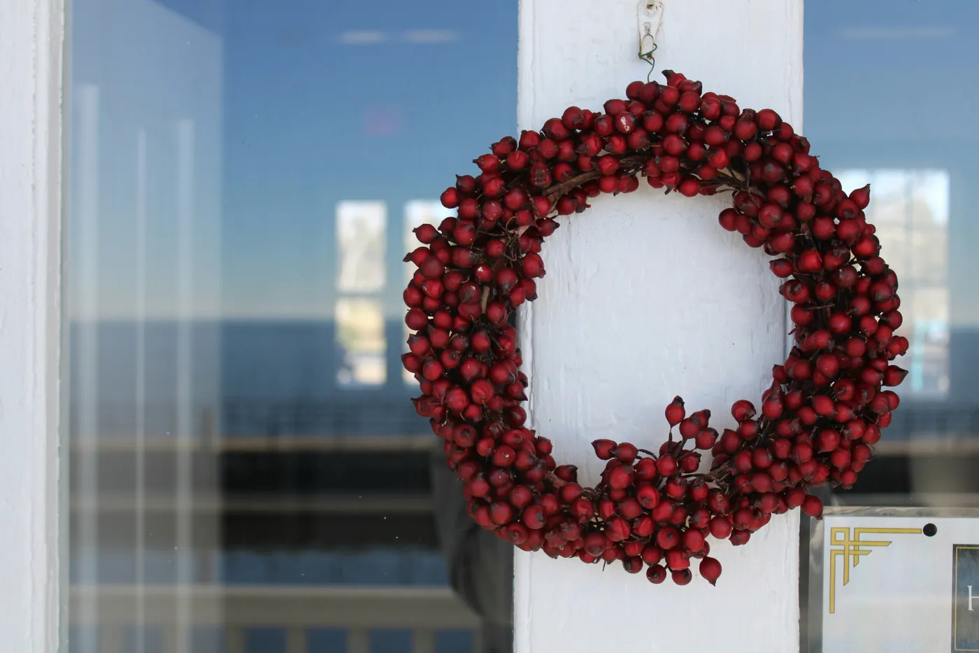 a red berry wreath hangs on a white door