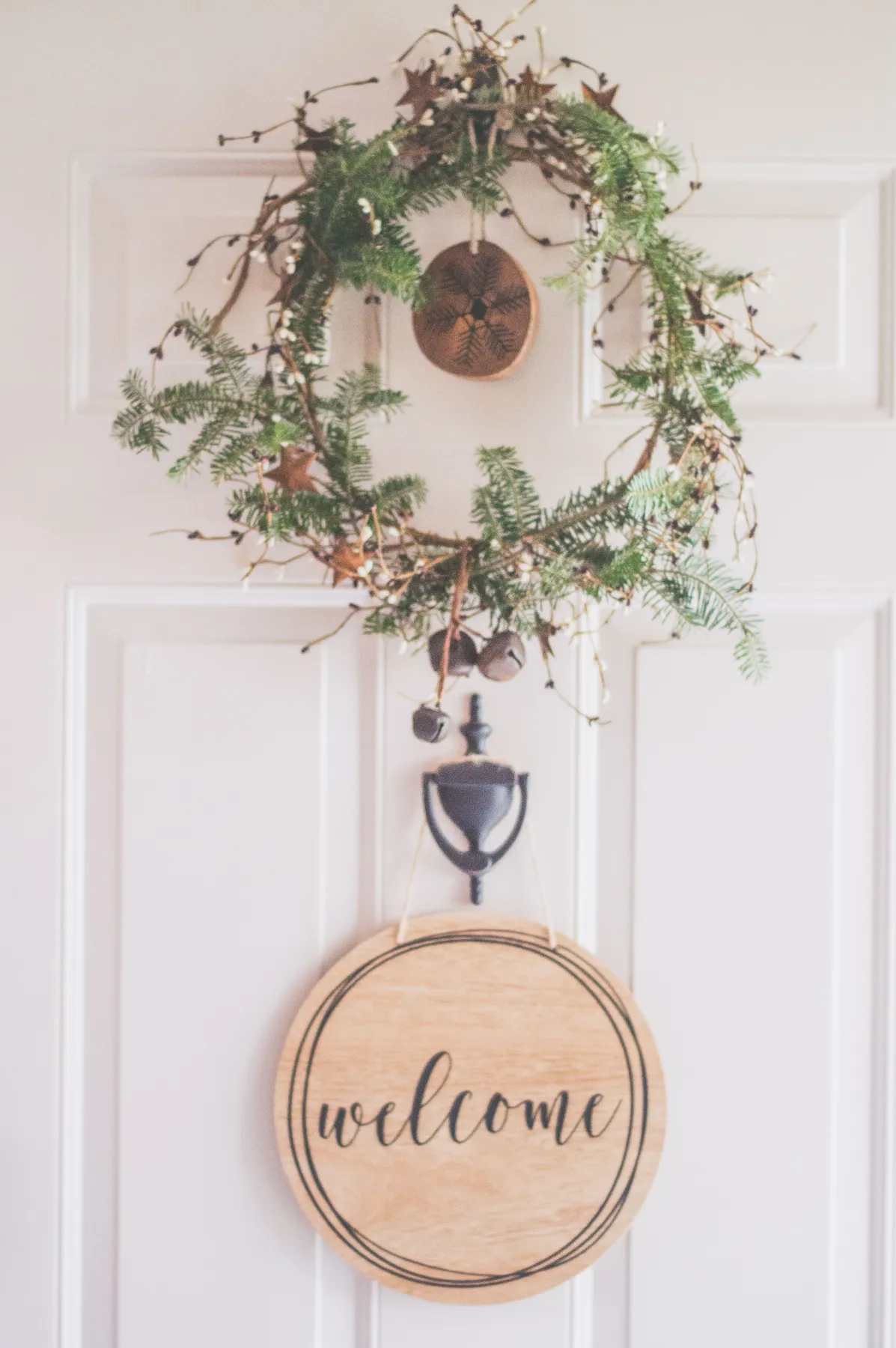 A rustic wreath with a welcome sign adorns a white front door, creating a cozy decor feel.