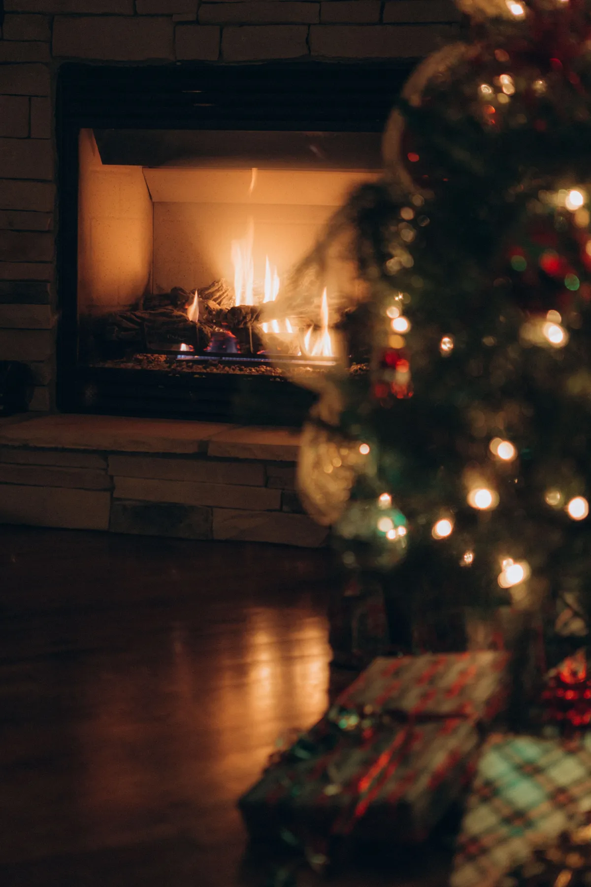 A warm fireplace and decorated Christmas tree create a festive holiday atmosphere.