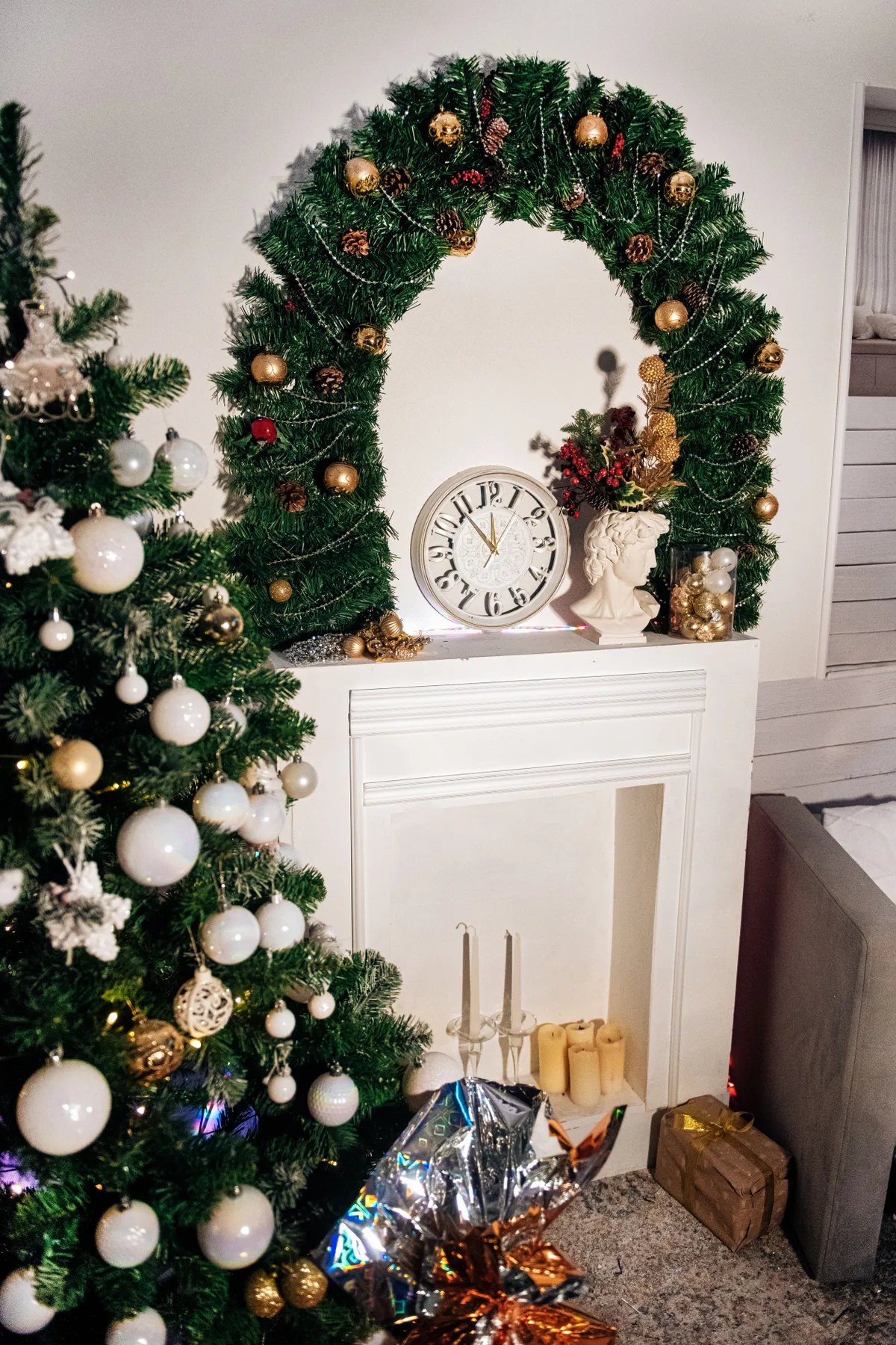 A warmly decorated fireplace with a Christmas tree, wreath, and festive ornaments.