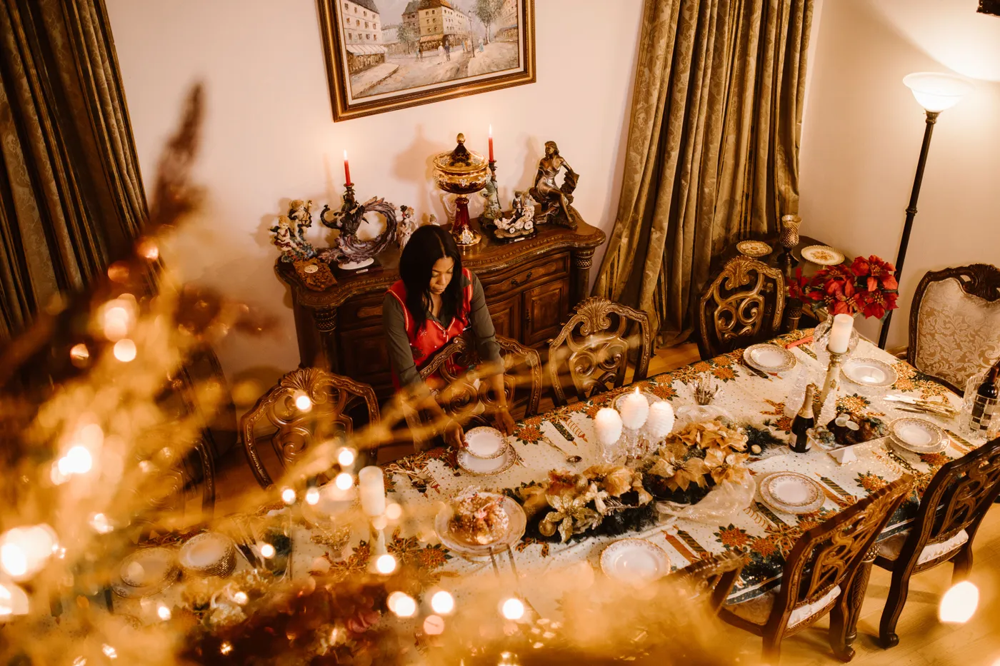 A woman preparing a festive Christmas dinner with elegant table settings and warm holiday decor.