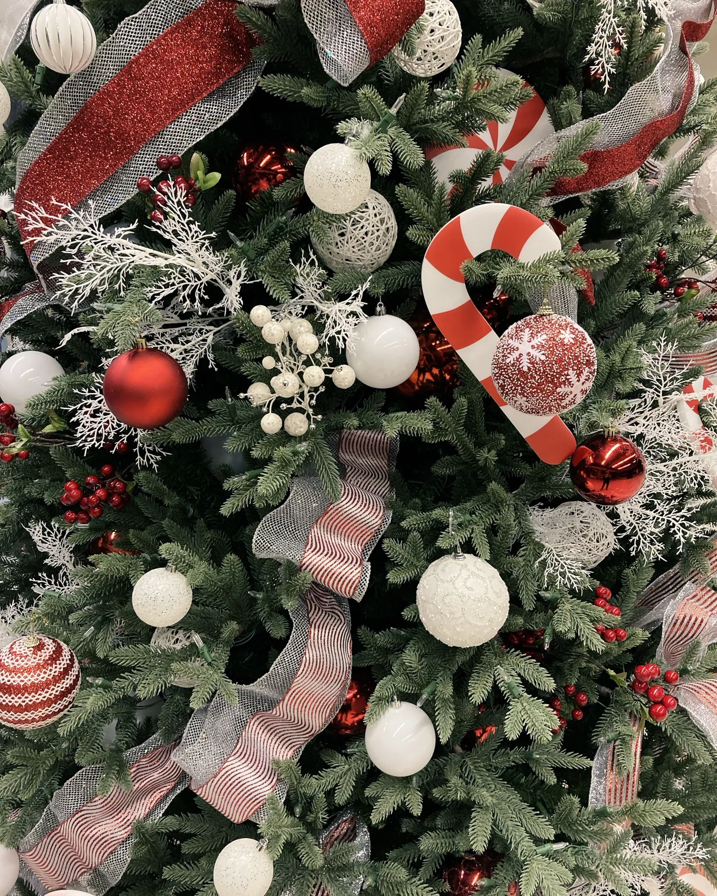 Beautifully decorated Christmas tree with ornaments, candy canes, and ribbons for a festive winter atmosphere.