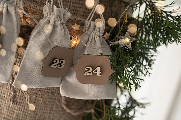 Bildagentur | mauritius images | Advent calendar with little gifts in linen  bags on rustic burlap.