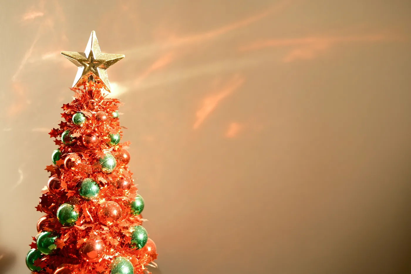 Bright red and green mini Christmas tree with golden star topper captures festive holiday spirit.