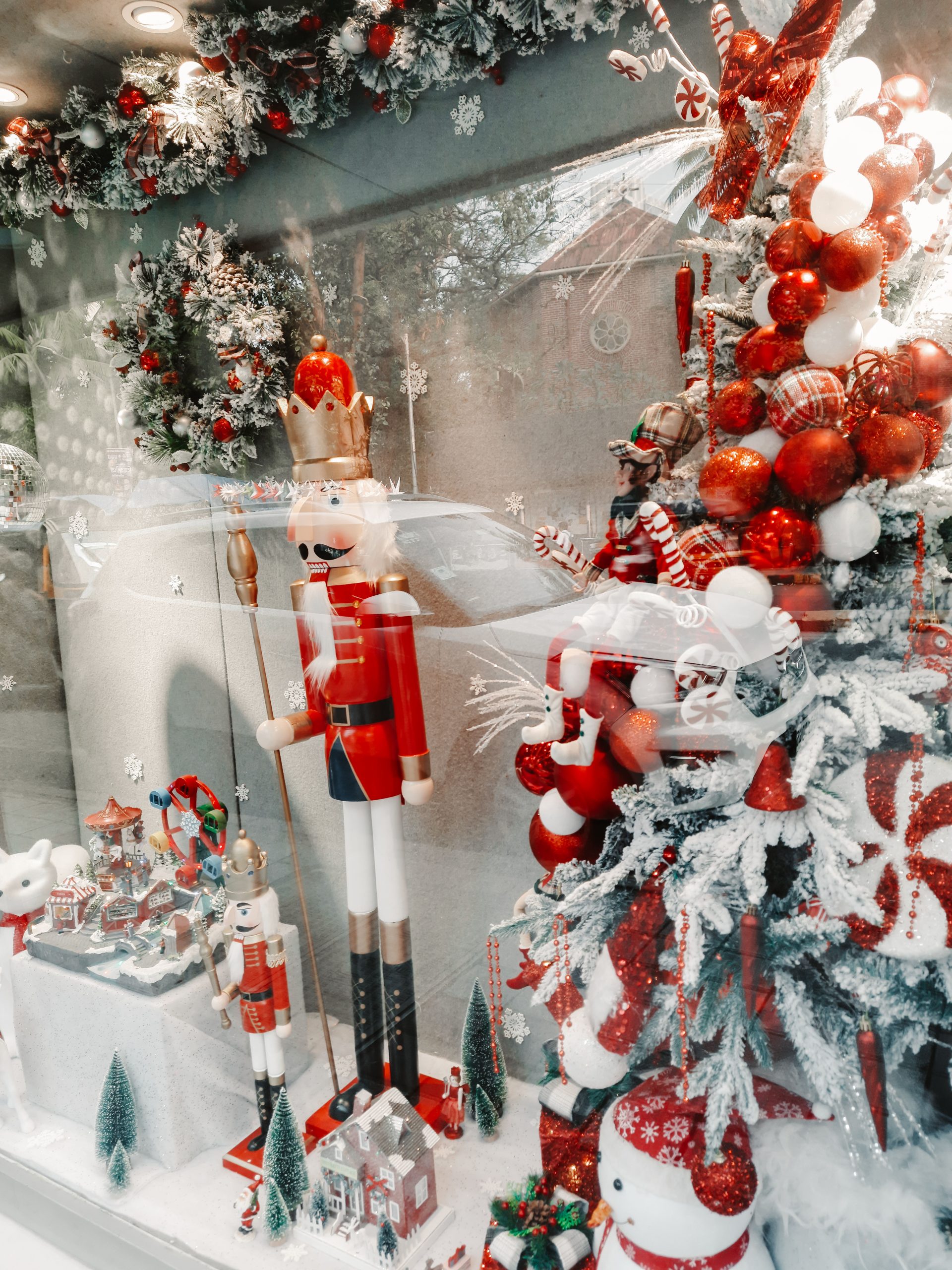 Charming Christmas window display featuring a nutcracker and festive decorations.