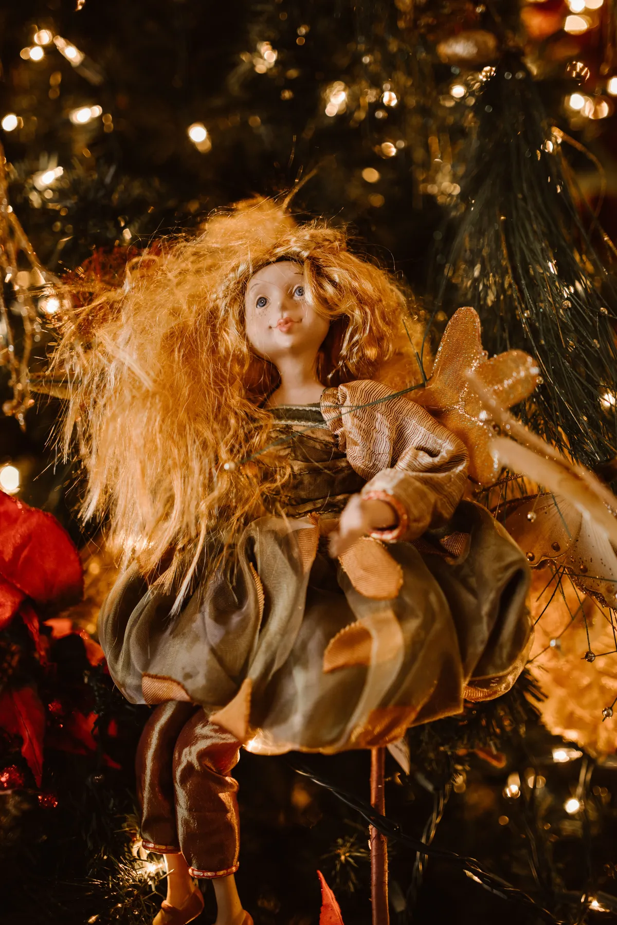 Charming fairy doll amidst twinkling Christmas tree lights and decorations.