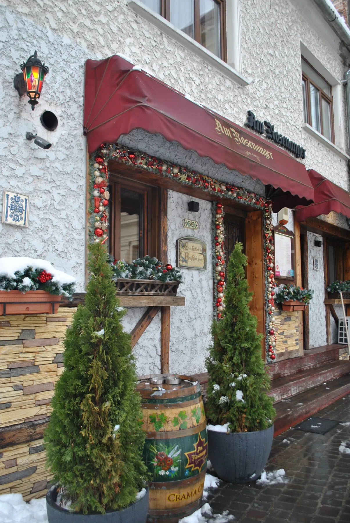 Charming restaurant exterior with festive decorations and snow in winter setting.