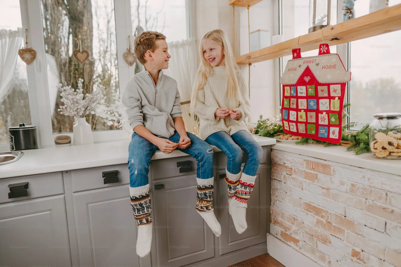 Children reading tasks from Christmas handmade advent calendar in a house  shape to countdown the days until Christmas on the wall in the room - Photo  on Unsplash+