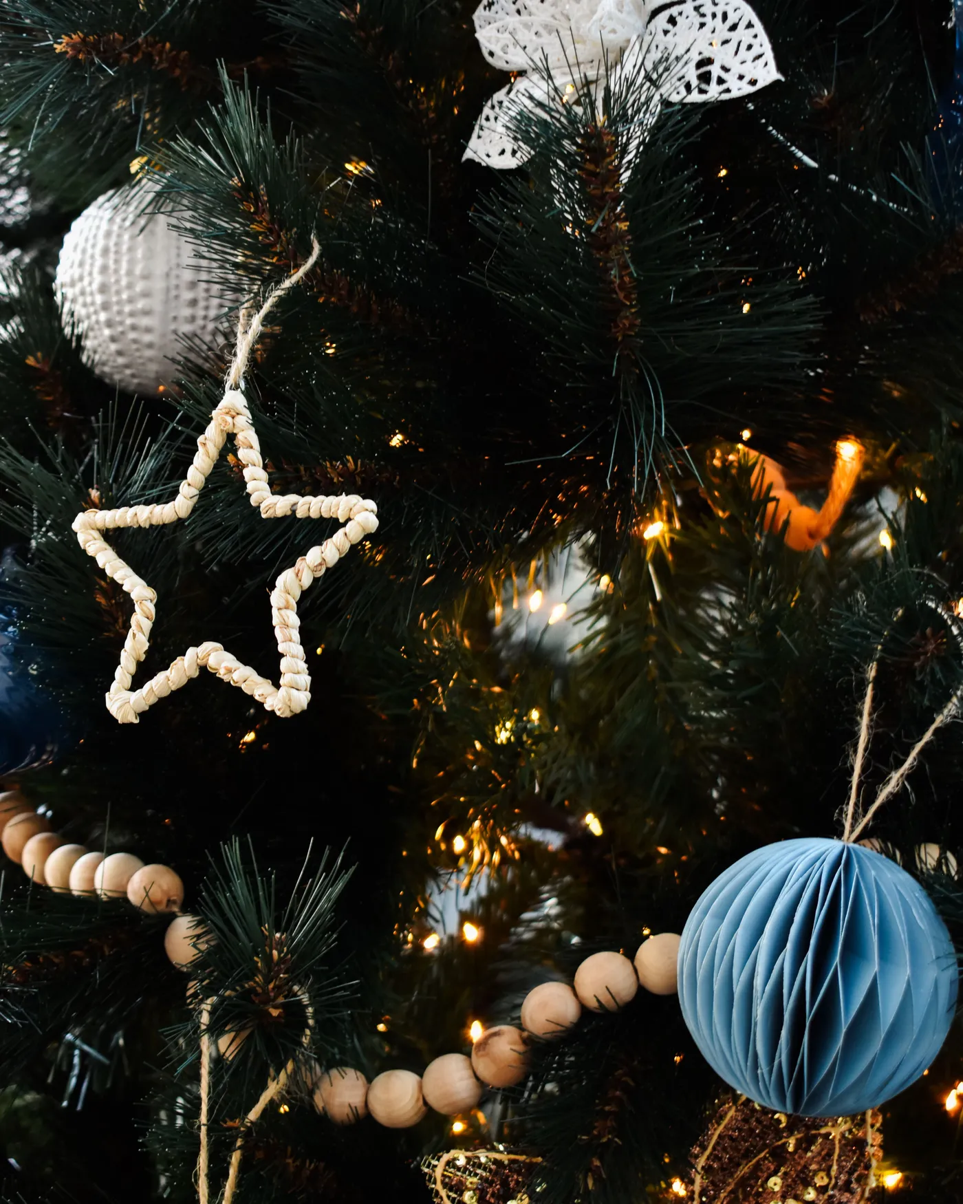Close-up of a Christmas tree with star and spherical ornaments, beautifully lit for the festive season.