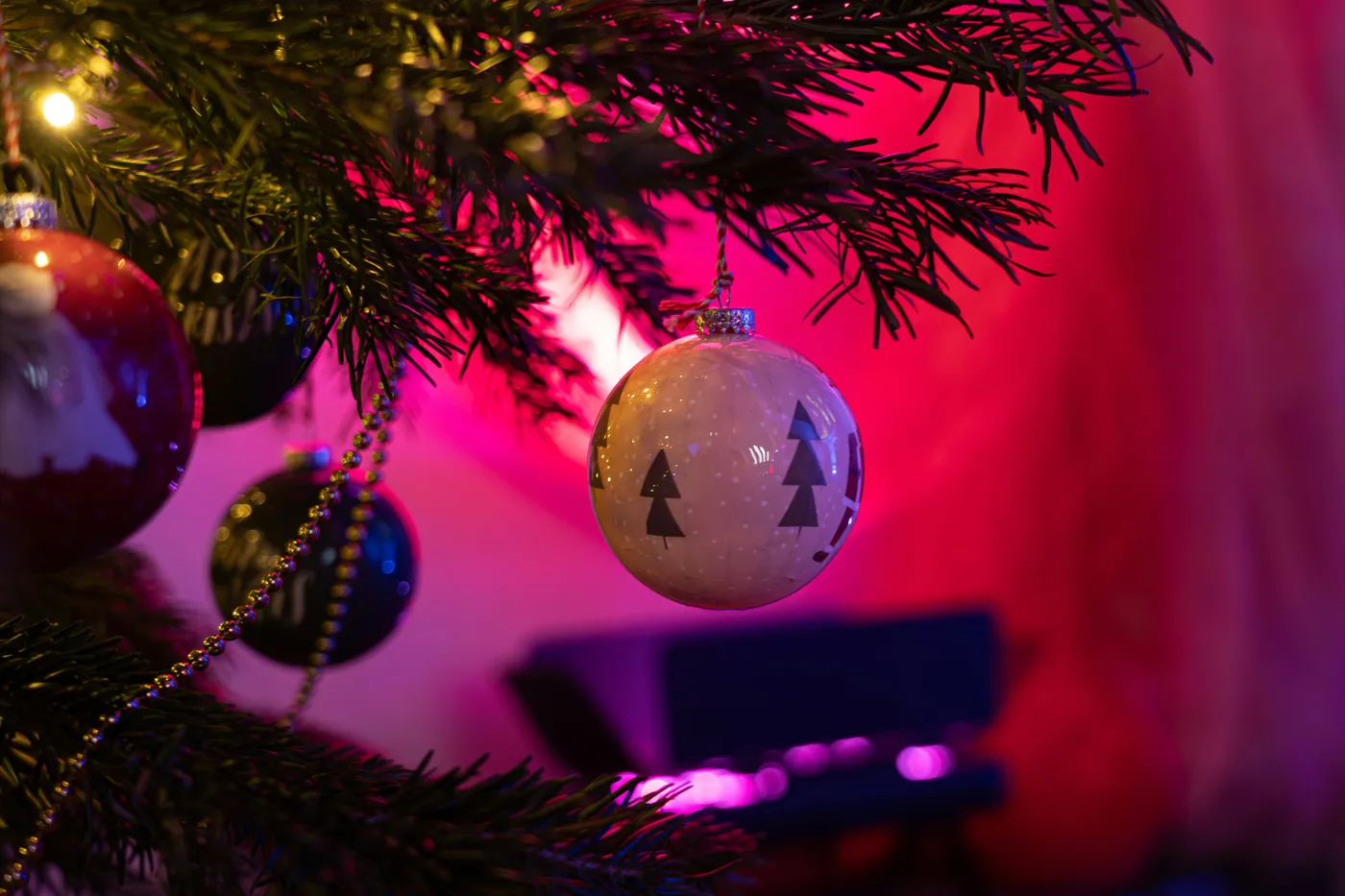 Close-up of a decorated christmas tree with pink lighting