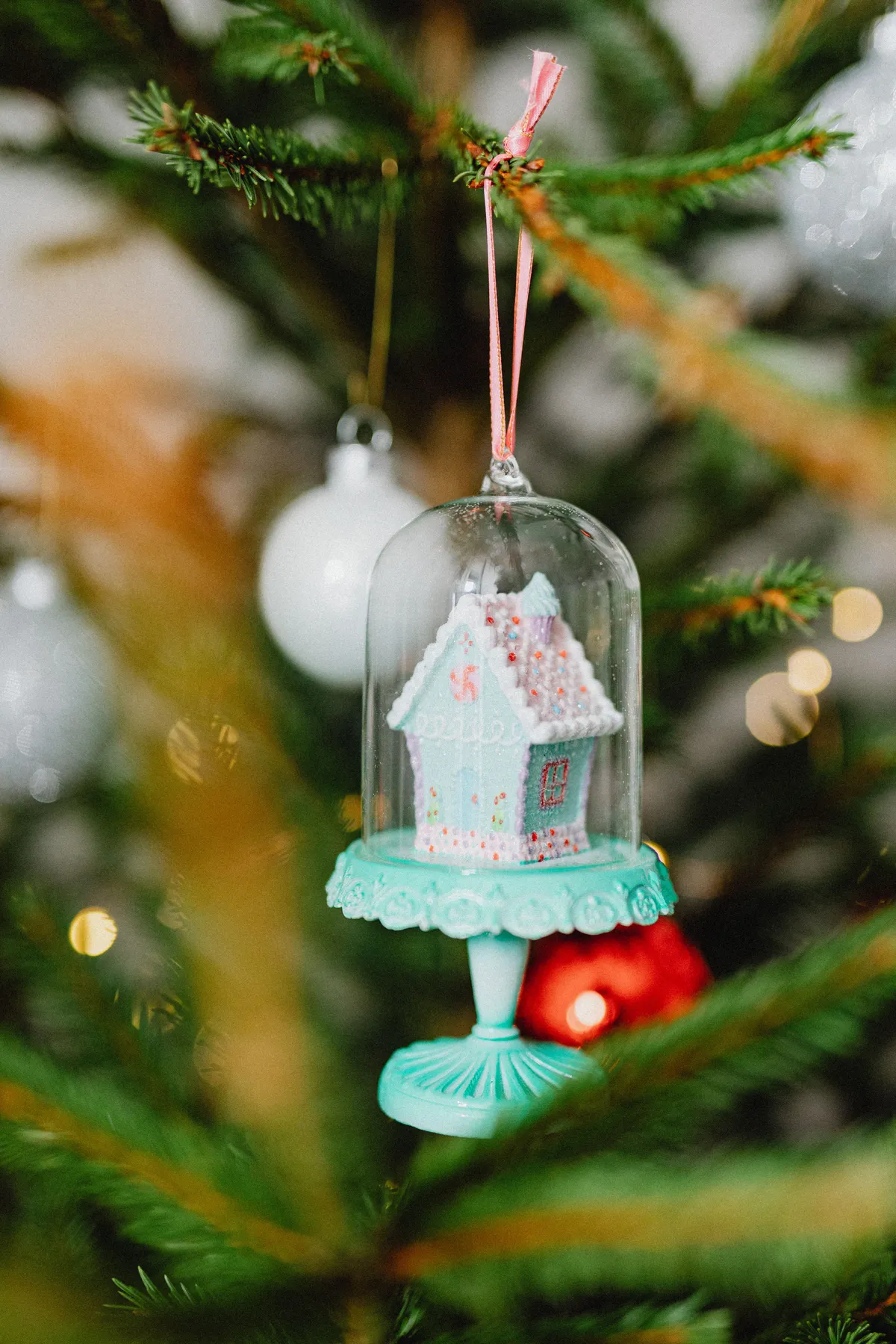 Close-up of a decorative gingerbread house ornament on a Christmas tree.