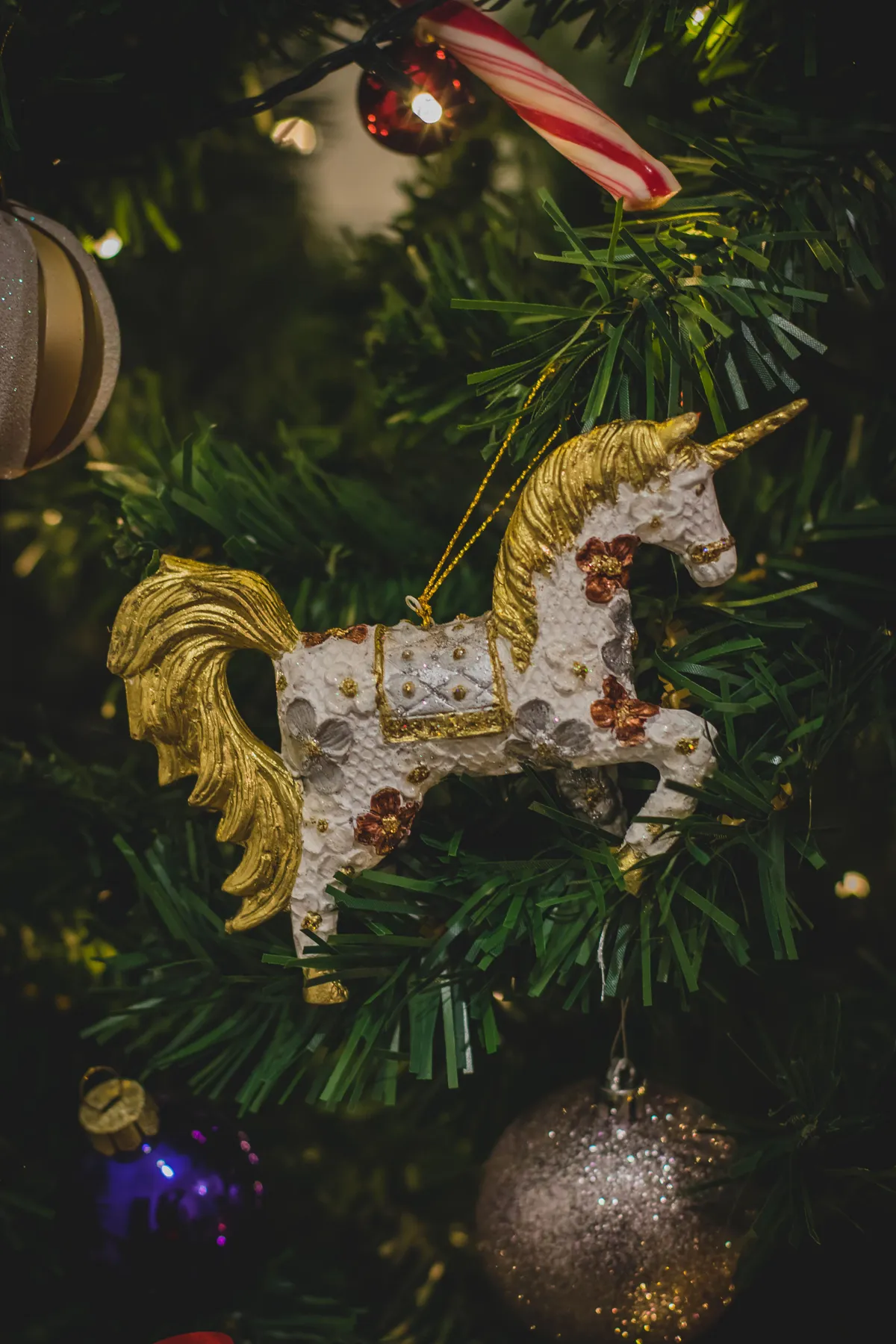 Close-up of a unicorn ornament hung on a decorated Christmas tree branch.
