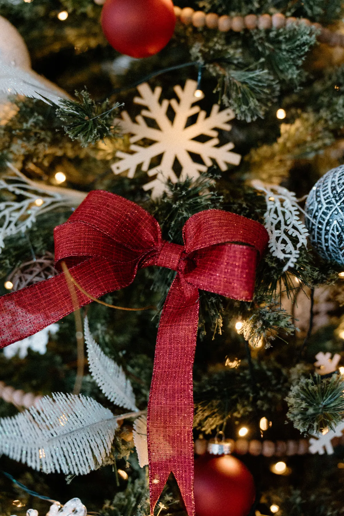 Close-up of Christmas tree decorated with a red bow and snowflakes.
