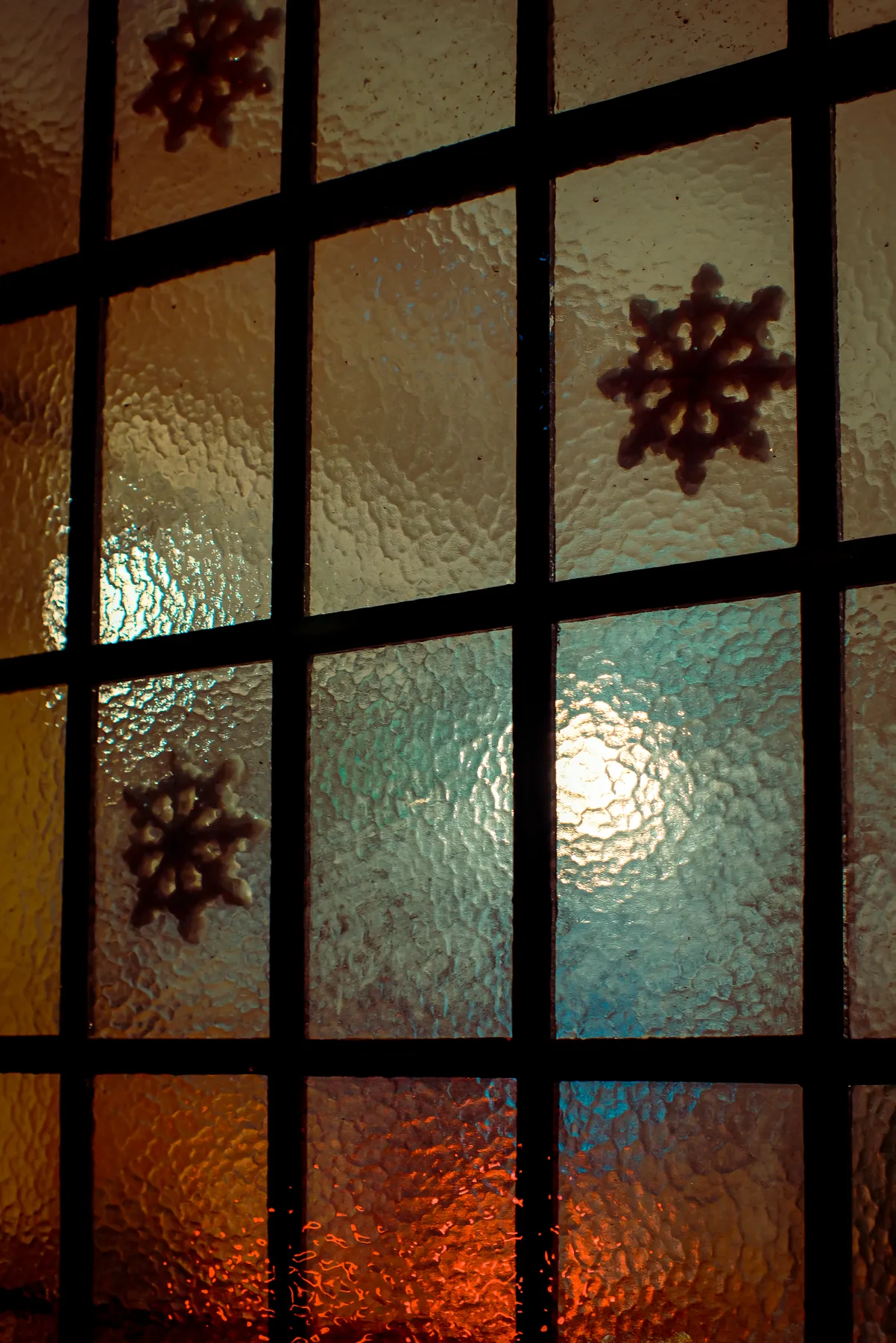 Colorful frosted glass window with snowflake shapes and warm lighting.