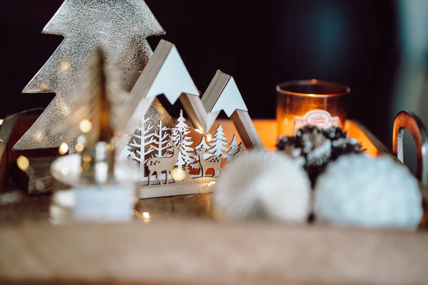 Cozy Christmas decor featuring miniature woodland scene and candlelight, perfect for holiday warmth.