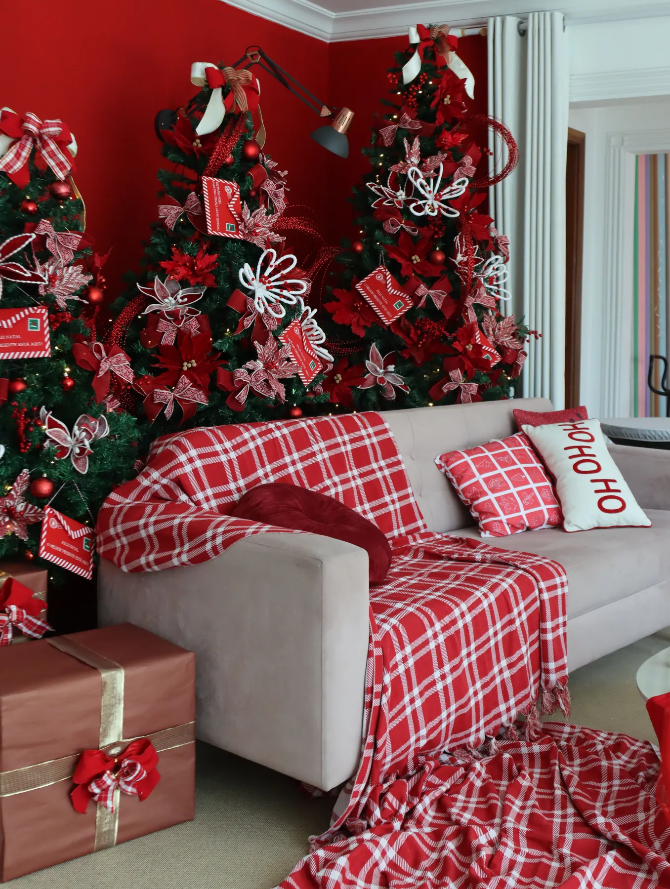 Cozy Christmas living room with decorated trees and festive red accents.