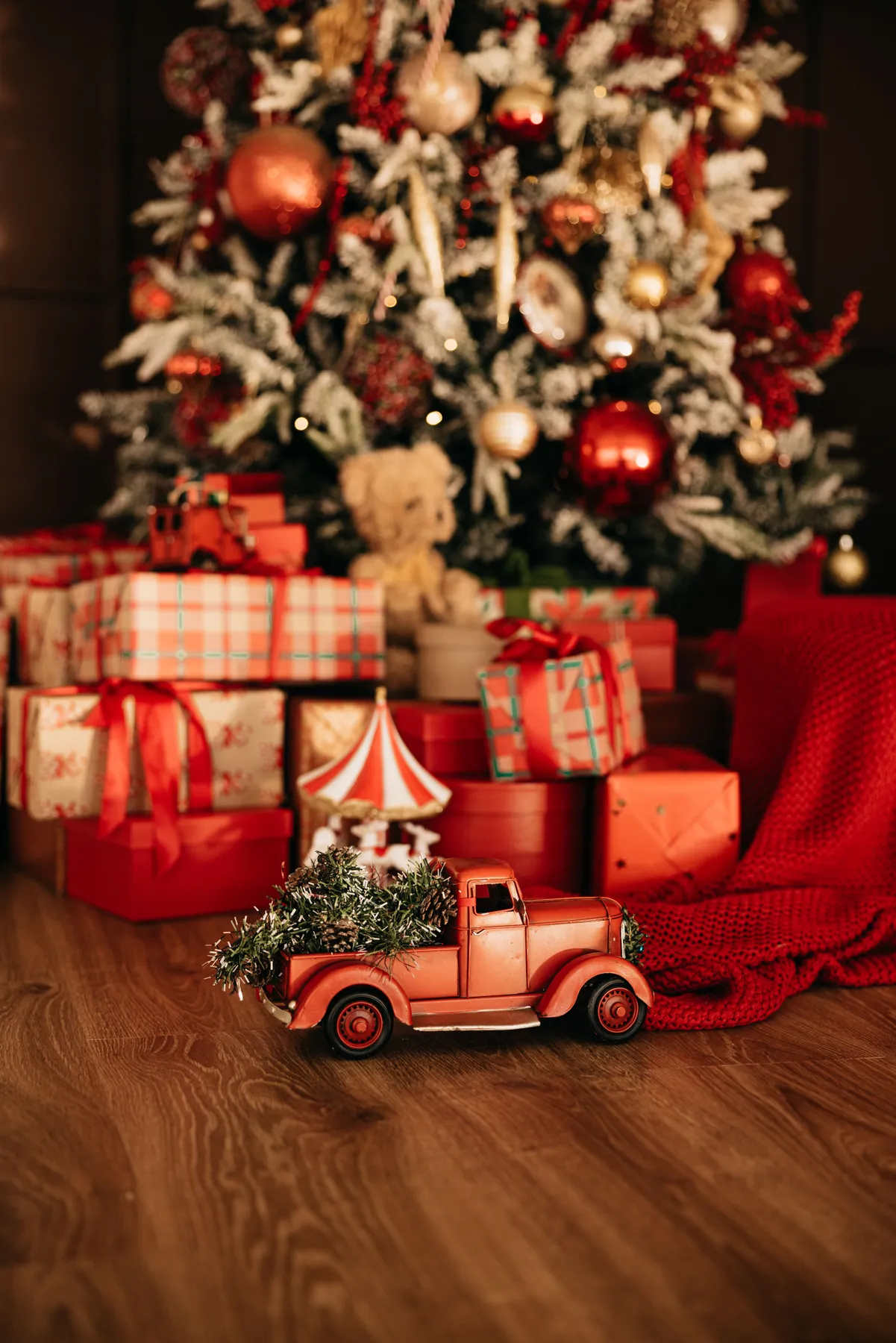 Decorated Christmas tree with wrapped gifts and a vintage toy truck in a cozy indoor setting.