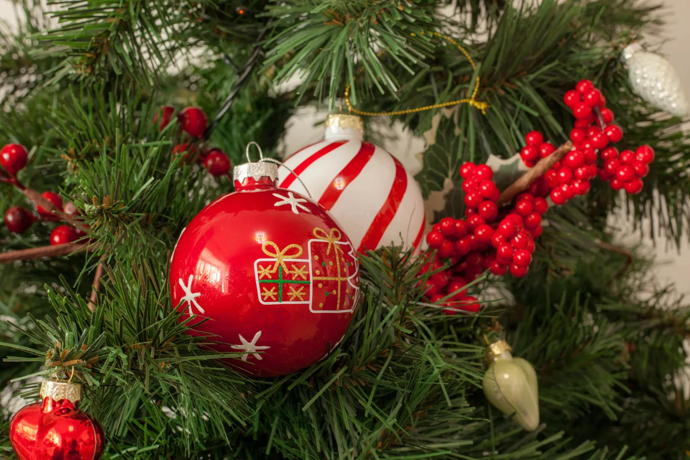 Decorative Christmas tree with red and white themed ornaments and festive greenery.