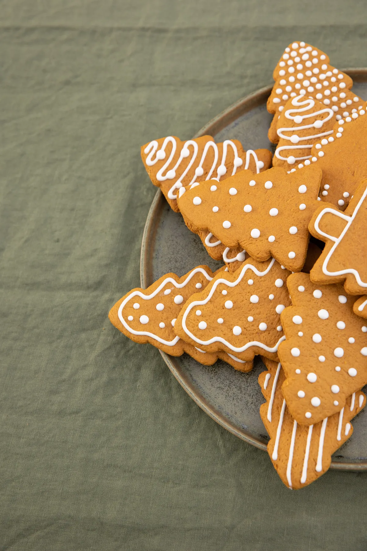 Delicious gingerbread Christmas tree cookies with icing on a plate, perfect for holiday celebrations.
