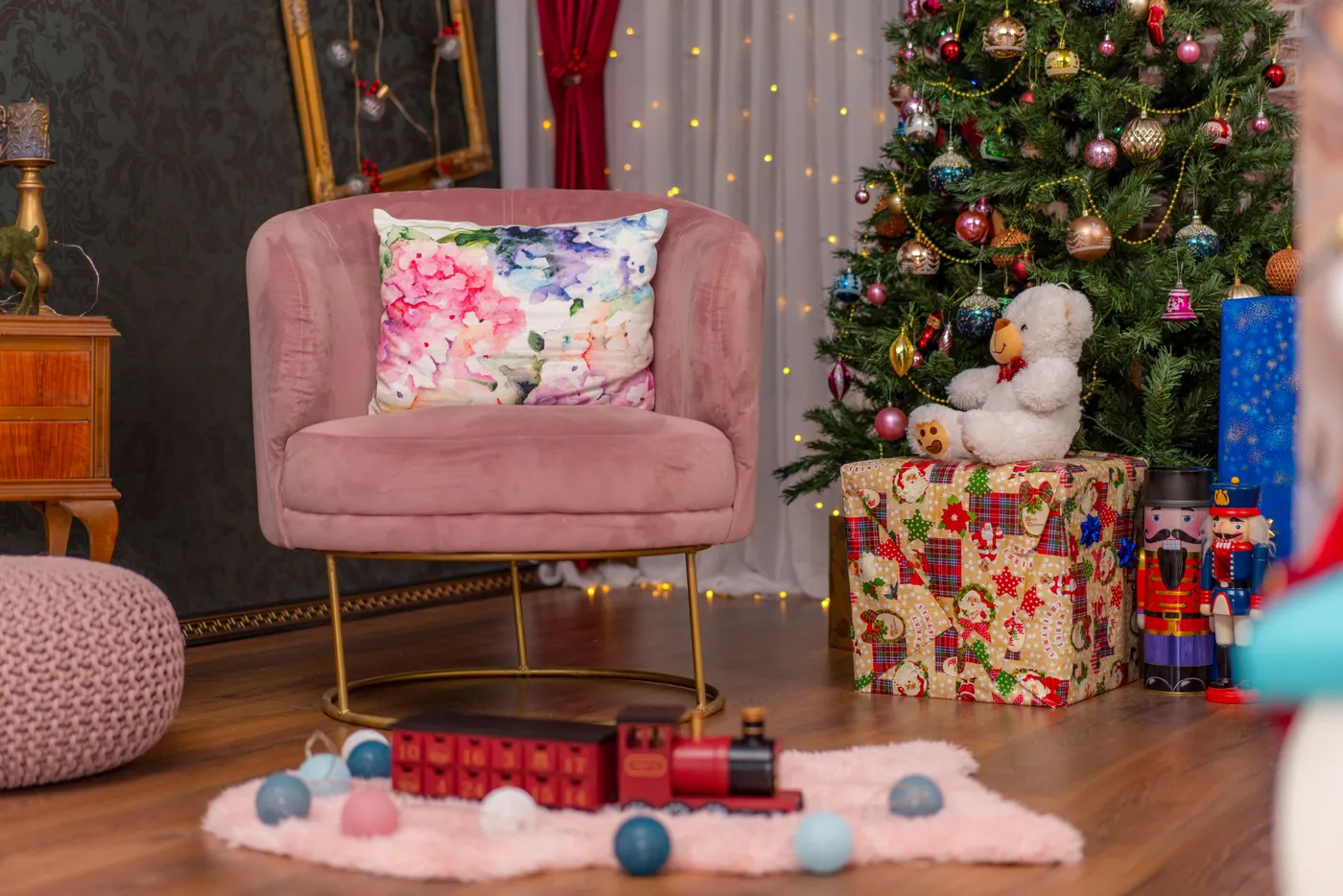 Elegant Christmas living room featuring a decorated tree, plush chair, and festive toy train.