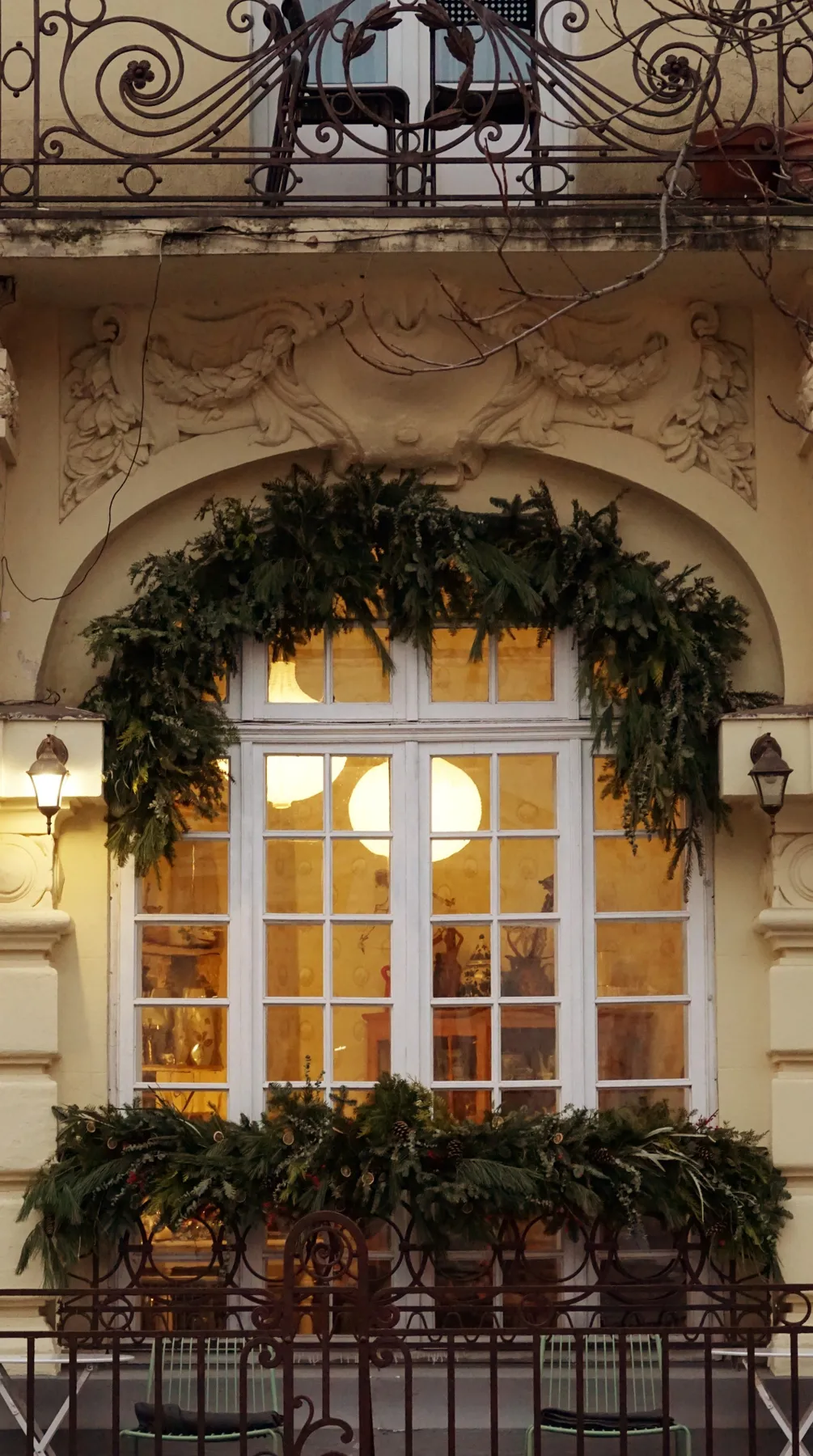 Elegant facade with festive greenery, ornate design, and warm window lighting.