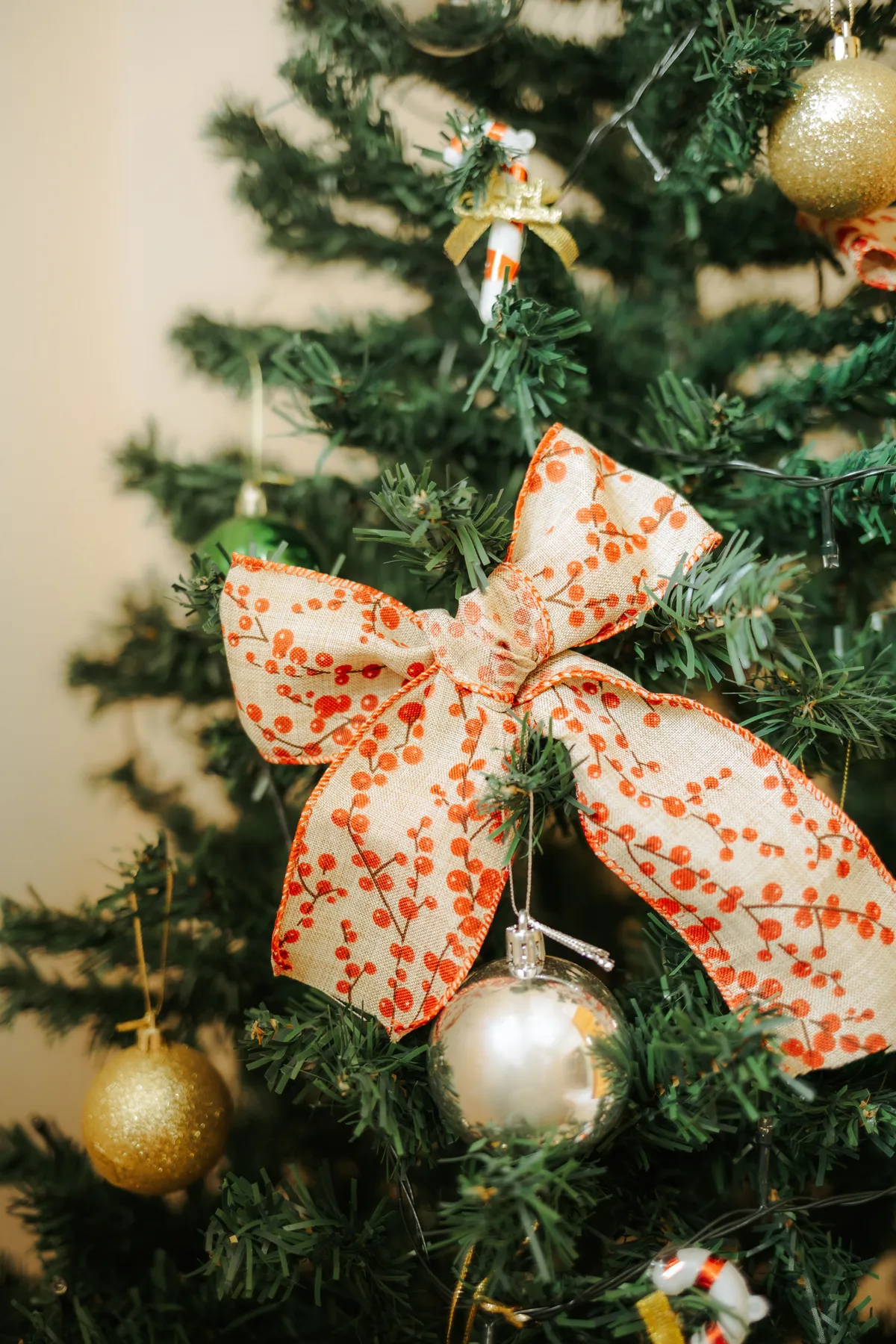 Festive Christmas tree with elegant decor and a large red ribbon, exuding holiday spirit.