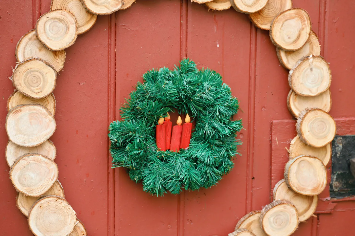 Festive Christmas wreath with red candles on a wooden door, evoking holiday spirit.