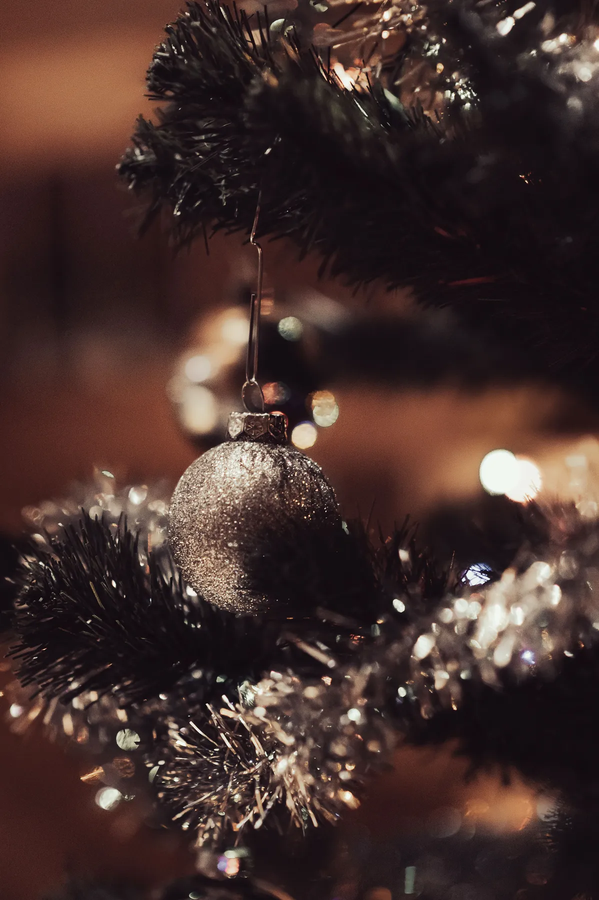 Festive close-up of a Christmas ornament hanging on a decorated tree branch, capturing warm holiday ambiance.