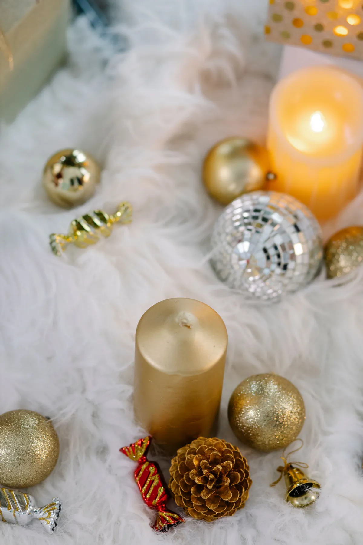 From above of festive baubles and burning candles placed on soft carpet in room during Christmas holiday