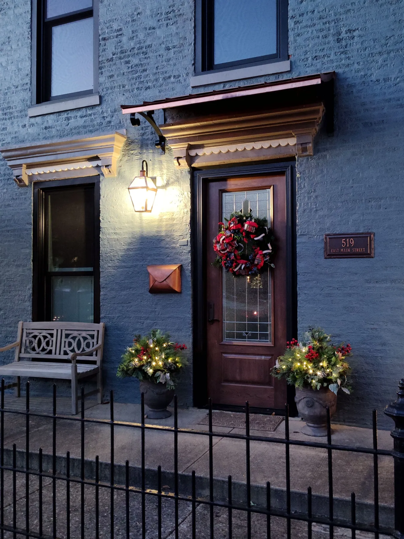 Front door with holiday decorations and warm lighting create a festive winter scene.