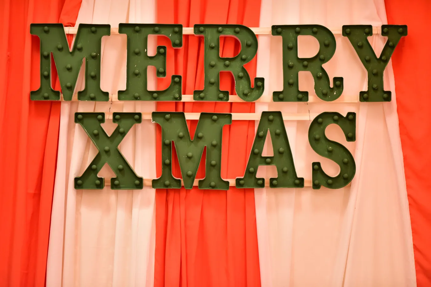 Green Merry Xmas sign against a festive red and white background, perfect for holiday decorations.