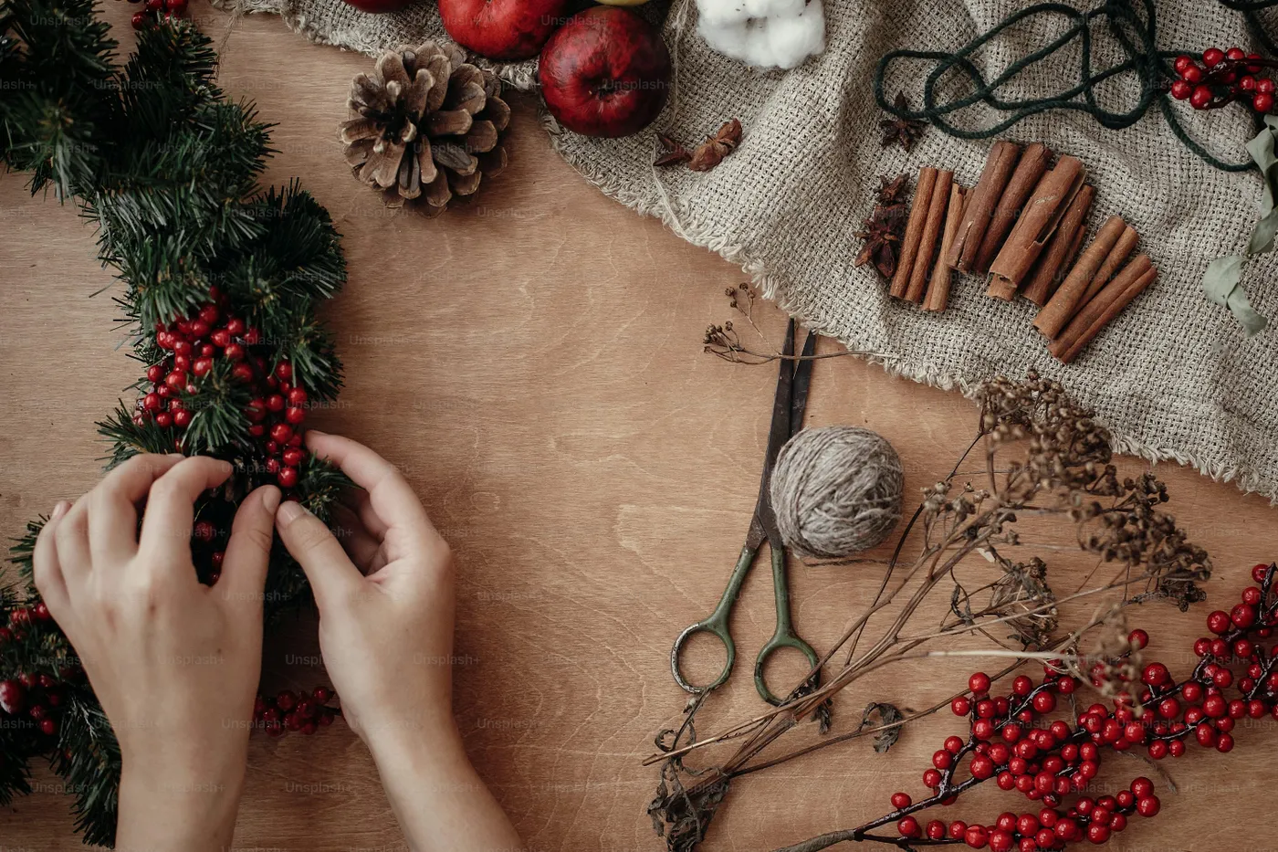 Hands arranging festive wreath on wood - Photo on Unsplash+
