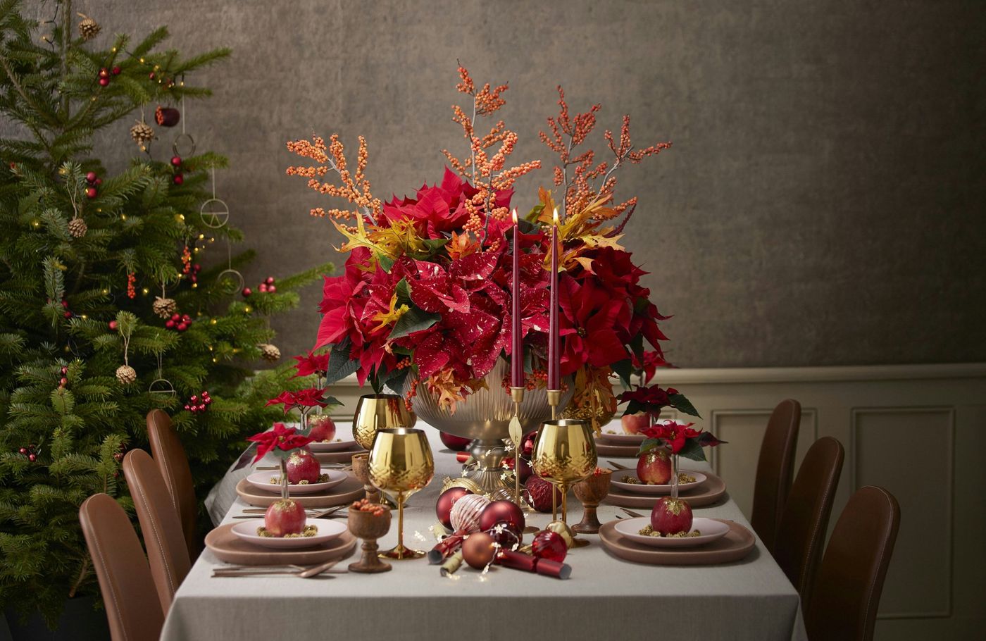 Poinsettias make a beautiful floral centrepiece for a Christmas table. In this opulent design in red, gold and bronze tones, they play the starring role with their shimmering colour contrasts. As pott