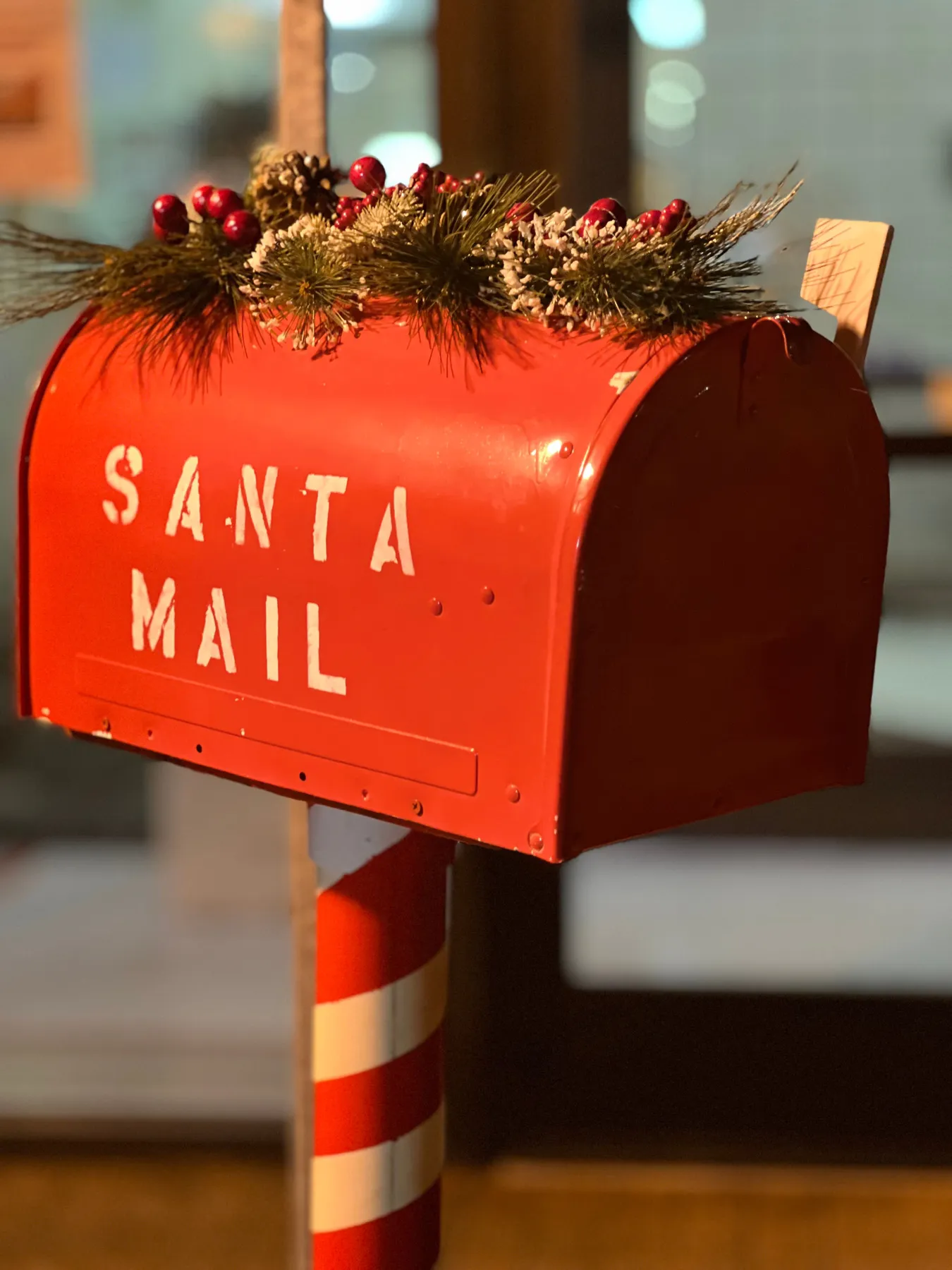 Red Santa mailbox adorned with pine branches and berries, capturing the festive spirit.