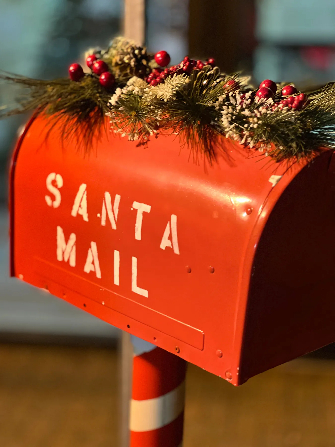 Red Santa mailbox decorated for Christmas with pine and berries.