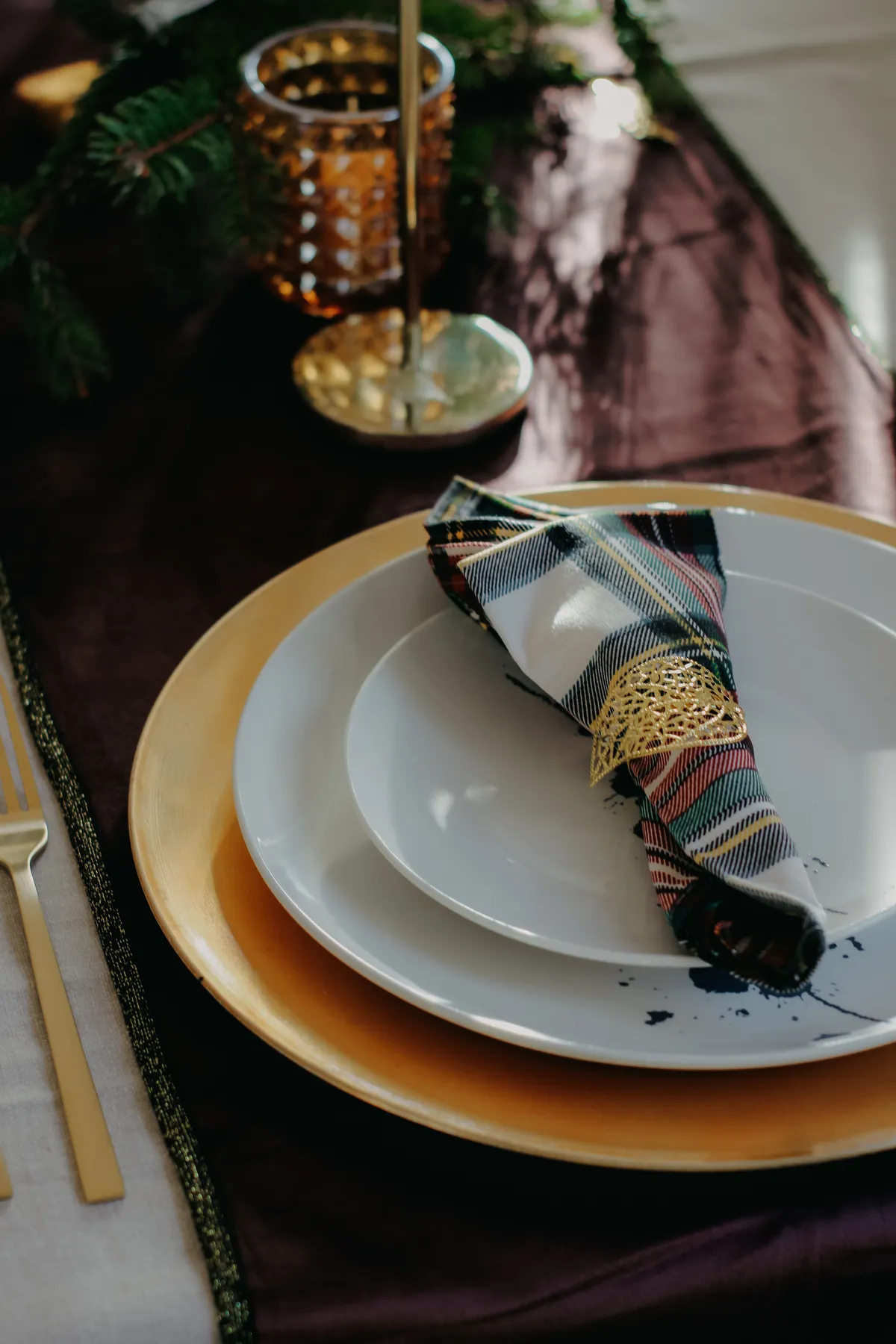 Stylish table setting with plates, gold cutlery, and festive decor for the holiday season.