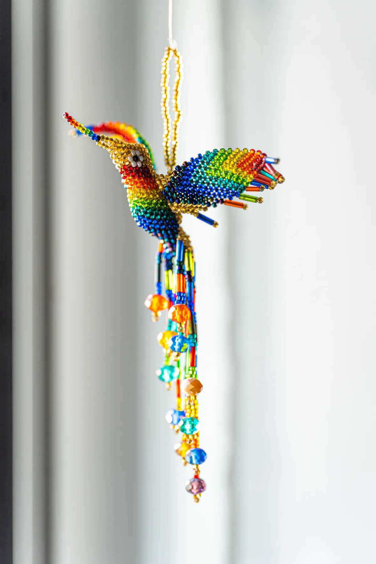 Vibrant beaded hummingbird ornament with tassels, perfect for artistic decor.