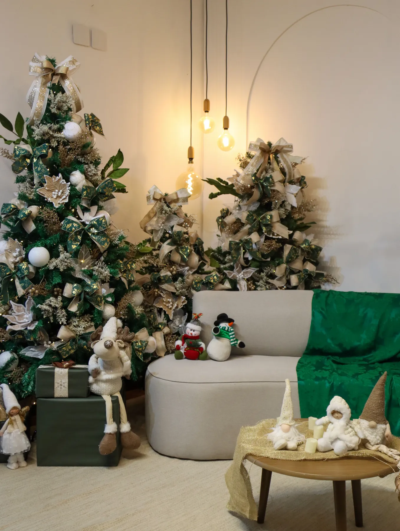 Warm, festive living room with decorated Christmas trees, cozy seating, and holiday decorations.